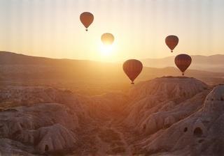 Hot air balloons flying over Cappadocia landscape at dawn